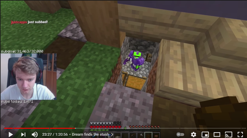A screenshot from Tommy's stream. Tommy stands above a hole in the ground. A few blocks down, Dream stands in his netherite gear in a cobblestone room. A few chests can be seen within the room. Dream holds a pickaxe and looks up at Tommy. Tommy's facecam shows that he's serious.